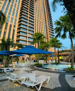 a pool with chairs and umbrellas in front of a building at Luxury Stay By Times Square Kuala Lumpur in Kuala Lumpur