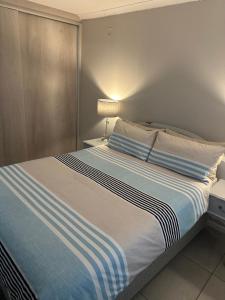 a bed with a blue and white striped blanket at Cozy at Cedarwood in Oakdale