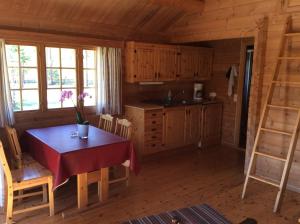 una cocina con mesa y sillas y una cocina con armarios de madera. en Furuly Camping, en Nordberg
