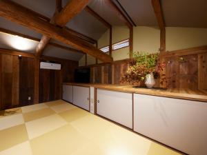 a large kitchen with white cabinets and wooden walls at Guest House NODOKA in Toyooka