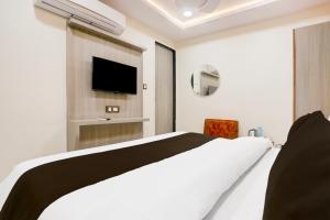 a white bedroom with a bed and a television at Hotel O BN RESIDENCY in Ahmedabad +21 photos