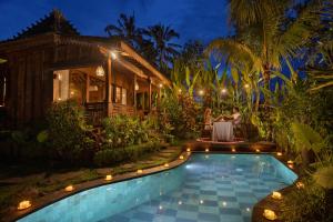 a couple sits at a table in front of a house at Santris Villas by GenuineHost in Ubud