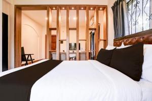 Un dormitorio con una gran cama blanca con ventana. en Collection O Dona Karen, en Goa