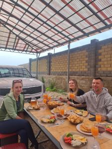a group of people sitting at a table with food at Son kol Keng suu guesthouse in Keng-Suu