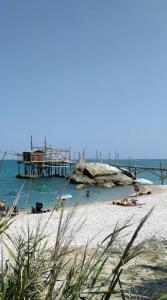 a beach with a pier and people laying on the sand at Villa Annamaria in Torino di Sangro