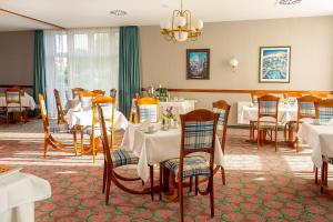 a restaurant with white tables and chairs and a chandelier at Hotel Kronprinz in Greifswald