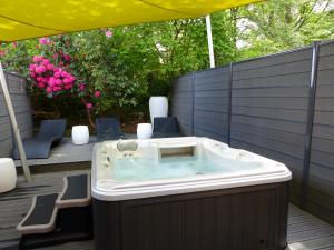 a hot tub on a deck with chairs and an umbrella at Best Western Auray le Loch in Auray