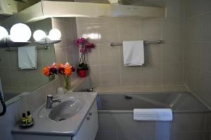 een badkamer met een wastafel en een bad met bloemen bij Domaine de la Reposée in Fermaincourt