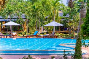 - une piscine avec des chaises longues et des parasols à côté d'un complexe dans l'établissement Dugong Resort Phu Quoc, à Duong Dong