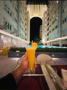 a person holding a glass of orange juice at a table at Sayeman Heritage Residence in Cox's Bazar