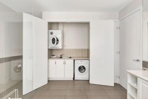 a white kitchen with a washer and dryer at Next to Bliss Luxury Guesthouse in Bright