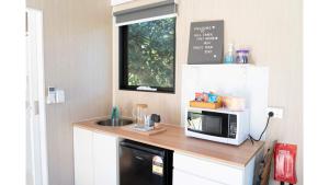 eine kleine Küche mit Mikrowelle und Spüle in der Unterkunft Hill Creek Tiny House 4 by Tiny Away in Perwillowen + 15 Fotos