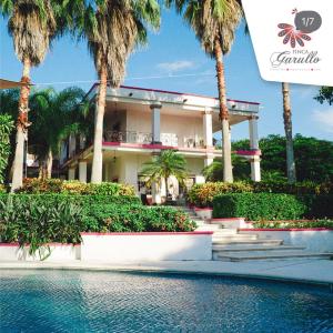 a building with palm trees in front of the water at Finca Garullo Hotel Boutique in San Rafael