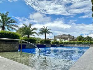 a swimming pool with blue water and palm trees at Angel's Place Torre De Manila, Cozy 1BR Condo, Sunset View Near all Attractions in Manila