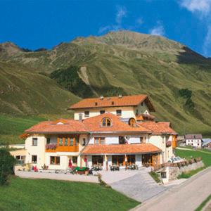 uma casa grande com uma montanha ao fundo em Hotel Alpenjuwel em Melago