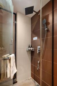 广州Locals Hotels Guangzhou Sports Center Linhe West Subway Station Branch的带淋浴和玻璃门的浴室 更多8张照片