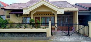 a small yellow house with a black fence at Gestur First House Syariah Hostel in Padang