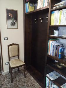 uma cadeira sentada ao lado de uma estante de livros com livros em B&B A Casa Di Nonna em Fondi