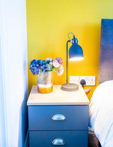 a table with a lamp and a vase of flowers on it at Mesh Accommodation Spacious Ensuite House for Contractors with Free Parking in Willesborough