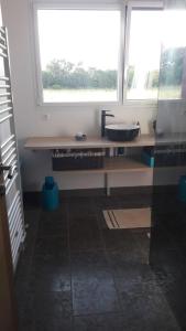 a bathroom with a counter with a sink and a window at Maison bois à la campagne in Marnay