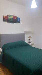 Una cama con un edredón verde en un dormitorio. en 2 ambientes fundacion hospitalaria, en Buenos Aires 1 foto más