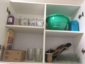 Un estante de cocina con platos de vidrio y un tazón verde. en 2 ambientes fundacion hospitalaria, en Buenos Aires