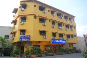 un bâtiment jaune avec un panneau devant lui dans l'établissement Yellow Mansion Hotel, à Malacca
