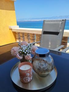 a candle and a vase with flowers on a table at Apartmani Kod Barbe in Vir