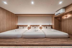 two white beds in a room with a wall at Apartment Hotel 11 Dotonbori4 in Osaka