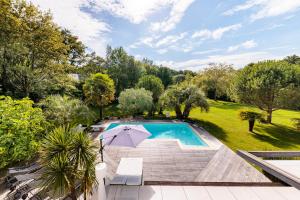 einen Blick über einen Pool mit Sonnenschirm in der Unterkunft Villa Markaly in Vigneux-de-Bretagne