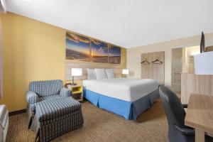 ein Hotelzimmer mit einem Bett und einem Stuhl in der Unterkunft Days Inn by Wyndham Fort Wayne in Fort Wayne