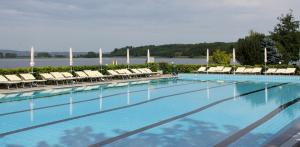 a large swimming pool with lounge chairs and a lake at Anthares World Resort in Candia Canavese