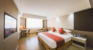 a hotel room with a bed and a television at Downtown Hotel in Zhuhai