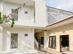 a white house with a staircase and a balcony at Bilqis Homestay Syariah Mitra RedDoorz in Wonosobo