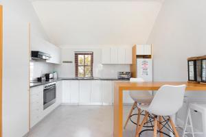a white kitchen with a wooden table and white chairs at Winelands Golf Lodges 8 in Stellenbosch