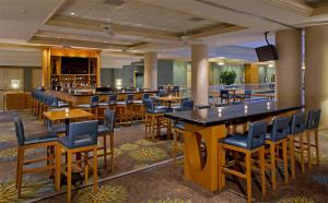un restaurant avec des tables et des chaises et un bar dans l'établissement Hyatt Regency Orlando International Airport Hotel, à Orlando