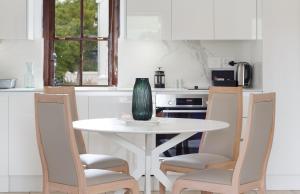 a white kitchen with a white table and chairs at Winelands Golf Lodges 9 in Stellenbosch