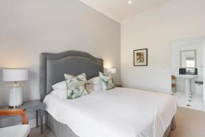 a white bedroom with a large white bed with pillows at Winelands Golf Lodges 9 in Stellenbosch
