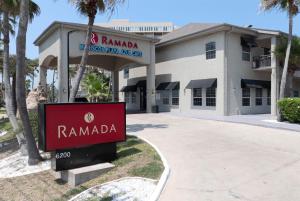 a sign in front of a building with palm trees at Ramada by Wyndham & Suites South Padre Island in South Padre Island