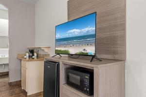a flat screen tv on top of a entertainment center at Ramada by Wyndham & Suites South Padre Island in South Padre Island