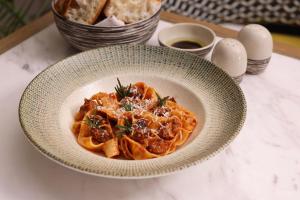 a bowl of pasta with meat and cheese on a table at InterContinental Bangkok by IHG in Bangkok