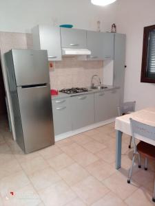 a kitchen with a stainless steel refrigerator and a table at Le Onde di Rossella in Torre Lapillo