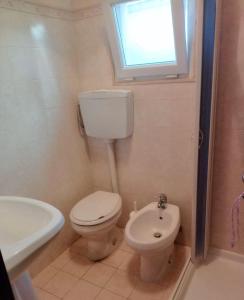 a bathroom with a toilet and a sink and a window at Le Onde di Rossella in Torre Lapillo +24 photos