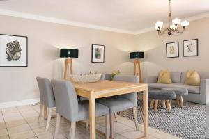 a dining room with a table and chairs and a couch at Winelands Golf Lodges 12 in Stellenbosch