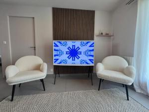 a living room with two chairs and a television at les colibris in Passy