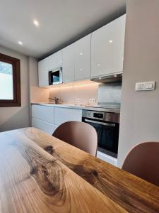 a kitchen with white cabinets and a wooden table at les colibris in Passy +29 photos