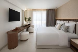 a white bedroom with a large white bed and a desk at Vione Paros in Ambelas