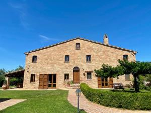 a large stone building with a grass yard at Casalantico in Corinaldo