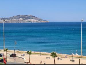 a view of a beach with palm trees and the ocean at Résidence Al Massira Fnideq in Fnidek
