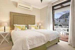 ステレンボッシュにあるWinelands Golf Lodges 15のベッドと大きな窓のある白い寝室 +16枚の写真